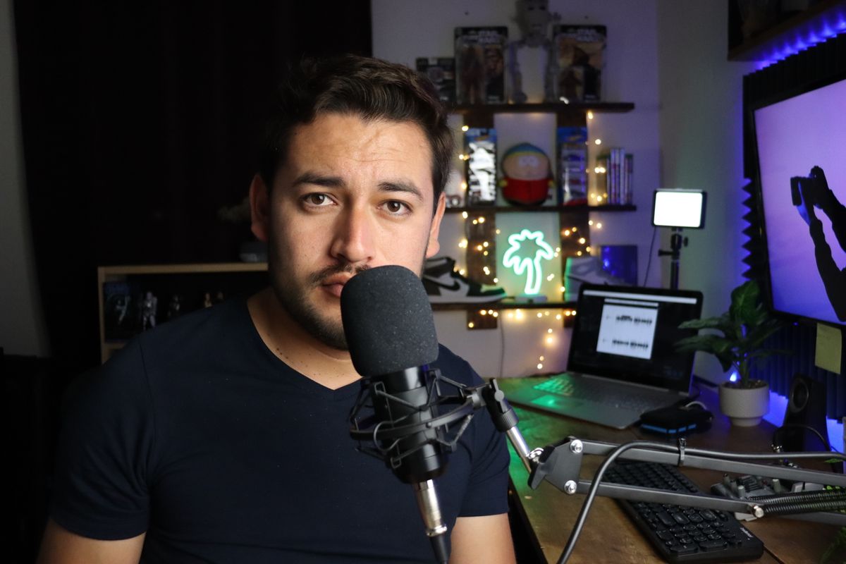 A streamer at a microphone in a neon-lit home studio