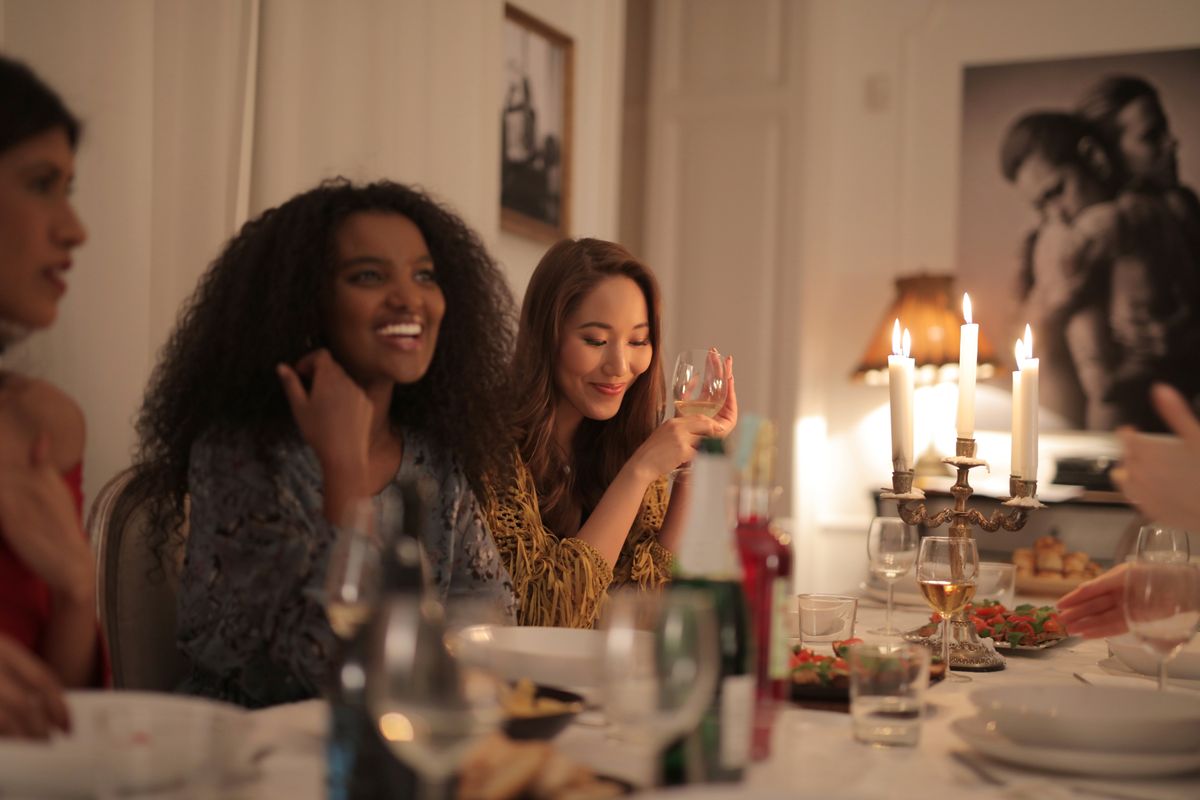Friends laughing over dinner by candlelight